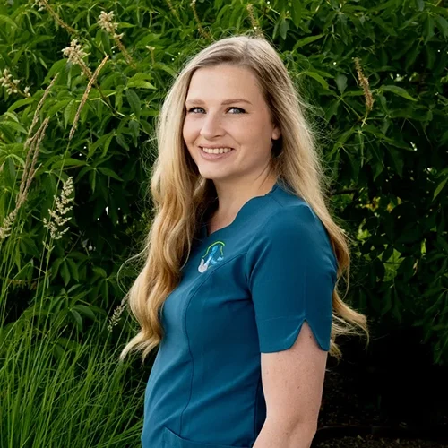 Eva smiling in front of green foliage