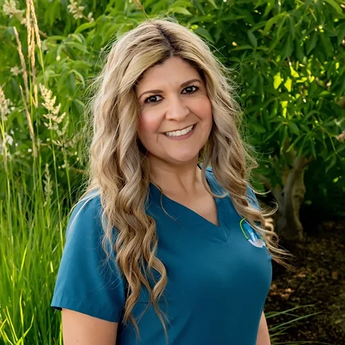 Monica smiling in front of a green foliage background